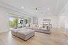 Living room with sofa, ottoman, high ceiling, and sliding doors to balcony