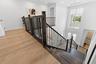 Upstairs landing with wood staircase and black iron railing