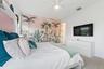 Bedroom with tropical palm mural, mounted TV, and dresser