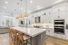 Kitchen with white cabinetry, large island, wood bar stools, and double wall ovens