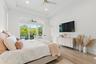 Bedroom with bed, nightstands, wall-mounted TV, ceiling fan, and sliding glass doors