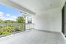 Covered balcony with railing, tile flooring, and lush green view