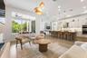 Open-concept kitchen with island, pendant lighting, and adjoining living area with glass doors to outside