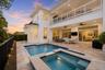 Backyard pool and spa with covered patio seating area at twilight