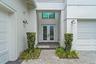 Covered front entry with glass door and manicured landscaping