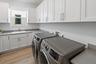 Laundry room with white cabinetry and wood flooring