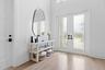 Foyer with round mirror, console table, and French doors to outside