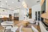 Sitting nook with swivel chairs, round side table, and wine display shelving near kitchen