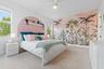 Bedroom with tropical palm tree mural and arched upholstered headboard