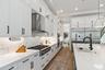 Kitchen with marble backsplash, professional-style range hood, and farmhouse sink