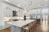 Large kitchen with oversized island, waterfall countertop, pendant lighting, and high ceiling