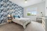 Bedroom with blue floral wallpaper, upholstered bed, and desk