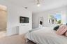 Bedroom with mounted TV, dresser, and mirror