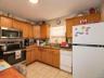 Kitchen featuring appliances with stainless steel finishes, light stone countertops, light tile patterned floors, and brown cabinets