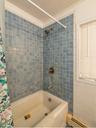 Bathroom featuring crown molding, baseboard heating, and shower / tub combo