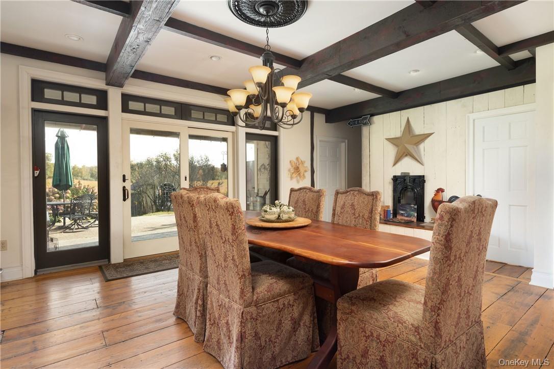 Dining space with  beamed ceiling, light hardwood / wood-style flooring, and coffered ceiling and a propane fire;place