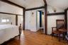 Bedroom featuring hardwood / wood-style flooring, wooden walls, vaulted ceiling with beams. Ensuite bath