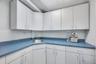 Corner workstation featuring extensive white cabinetry, speckled blue countertops, and an integrated stainless steel sink with a chrome faucet
