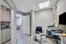 Professional workspace featuring light gray walls, wood-finish flooring, and a suspended ceiling with integrated lighting