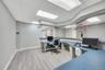 Reception area featuring a curved desk with a blue countertop, light wood-finish flooring, and a suspended acoustic tile ceiling with integrated light