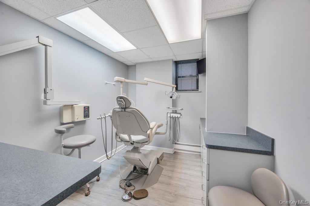 Professional medical examination room featuring light gray walls and wood-finish flooring