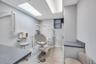Professional medical examination room featuring light gray walls and wood-finish flooring