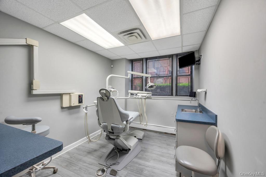 Dedicated clinical space featuring wood-finish flooring, light gray wall paint, and a dropped ceiling with integrated fluorescent lighting