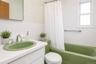 Bathroom featuring a green drop-in sink, white vanity, white tile wainscoting, green bathtub, and a window providing natural light