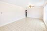 Spacious room featuring geometric tile flooring, crown molding, baseboards, and a ceiling fan with integrated lighting