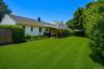 Expansive green lawn with a covered wood deck and mature perimeter landscaping