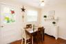 Dining area featuring terracotta-style tile flooring, a built-in white cabinet, and a wall-mounted shelving unit