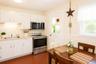 Eat-in kitchen featuring white cabinetry, stainless steel appliances, a tile backsplash, light-toned countertops, and wood-finish flooring