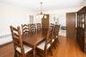 Hardwood flooring extends throughout this room, featuring a classic chandelier, crown molding, and a solid wood door frame