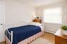 VIRTUALLY STAGED. Room featuring neutral wall tones, patterned wood-finish flooring, and a large window with blinds and valance