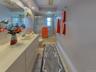 Bathroom featuring an integrated vanity sink, extensive countertop space, a tub with glass enclosure and a full-width mirror