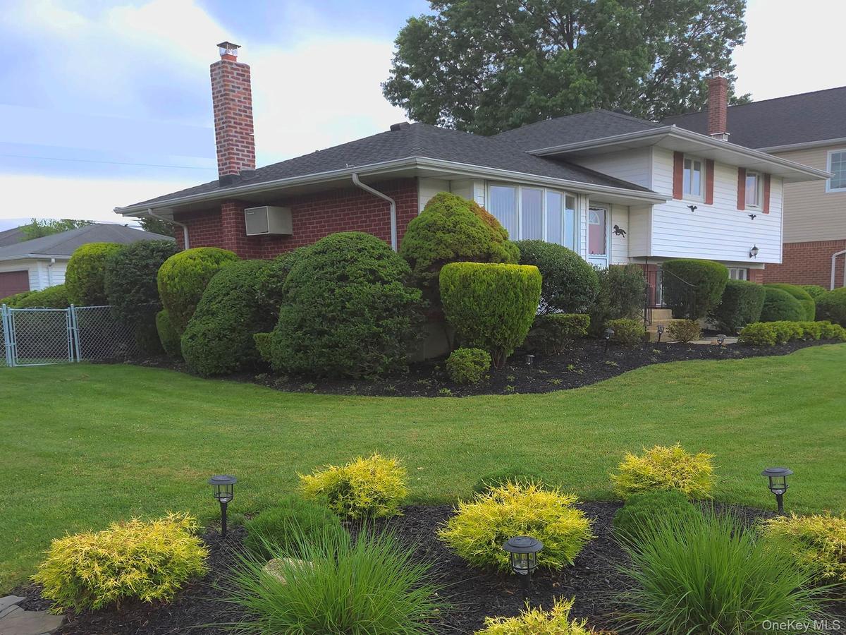Split-level residence featuring white siding, a dark shingle roof, and a red front door roof