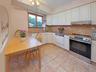 Kitchen featuring white cabinetry, a stainless steel range and hood, granite countertop, tile flooring, and a window