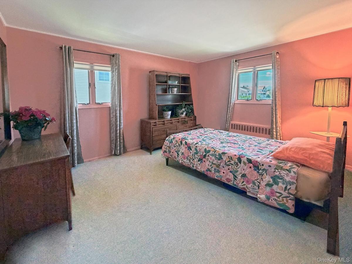 Carpeted room with two windows featuring blinds and drapes, and painted walls