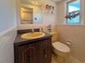 Corner vanity with a yellow oval basin, wood-finish cabinetry, and a mirrored medicine cabinet
