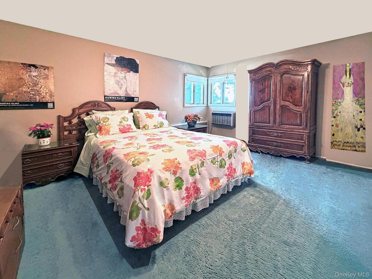 Bedroom featuring plush blue carpeting, a window-mounted air conditioning unit, and a built-in window providing natural light