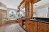 Elegant custom bath features dual sink and storage areas with built-in lighting, jetted garden tub, separate shower and walk-in closet