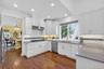 Kitchen with white cabinets, dark wood finished floors, light stone countertops, tasteful backsplash, and recessed lighting