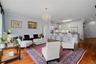 Another view of the living room emphasizing the open layout, beautiful chandelier, and primary suite entrance.
