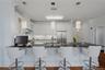 Alternate view of the kitchen, showcasing elegant pendant lighting, stainless steel appliances, and seating for four at the breakfast bar.