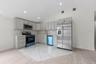 Modern kitchen featuring light gray cabinetry with gold-tone hardware, stainless steel appliances, a patterned tile backsplash, and recessed lighting