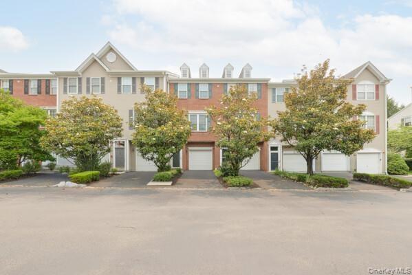 Townhome exterior featuring a dormer roofline, red brick accents.