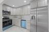 Kitchen featuring light-toned cabinetry with gold-toned hardware, stainless steel appliances, a white patterned backsplash, recessed lighting, and mar