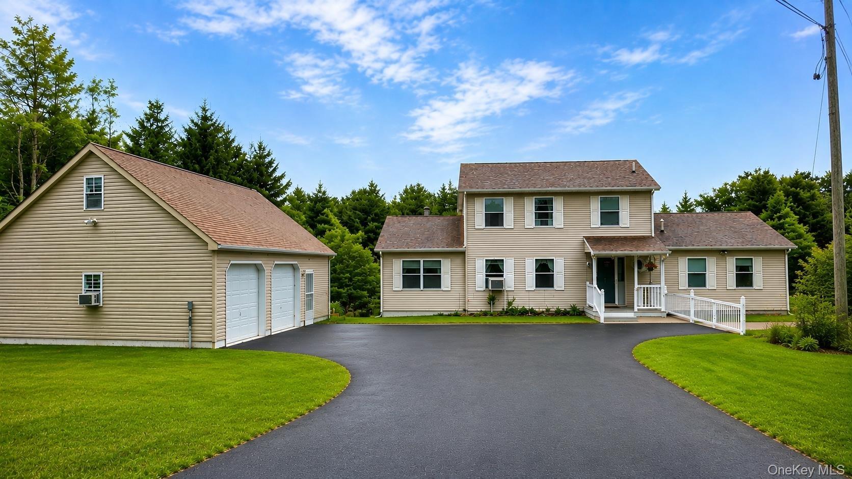 Expansive asphalt driveway leading to a two-story residence and a detached two-car garage