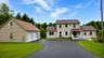 Expansive asphalt driveway leading to a two-story residence and a detached two-car garage