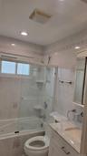 Bathroom featuring a jetted tub with glass enclosure, white vanity with stone countertop, recessed lighting, and tiled walls with decorative accents